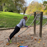 trainiert am playfit Beinheber-Liegestütz-Kombitrainer K05013 im Park mit Sand- und Rasenfläche