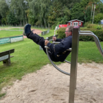 beim Beinheben im Stehen am playfit Beinheber-Liegestütz-Kombitrainer K05013 im Freien
