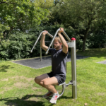 trainiert am playfit Oberkörpertrainer - Pressen K05029 im Park mit Rasenfläche