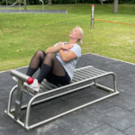 trainiert am playfit Bauchtrainer K05041 im Outdoor-Fitnesspark mit Fallschutzplatten